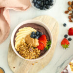 Acaibowl toppat med Paulúns Granola Hasselnötter & Dadlar, skivad banan, jordgubbar, blåbär och jordnötssmör.